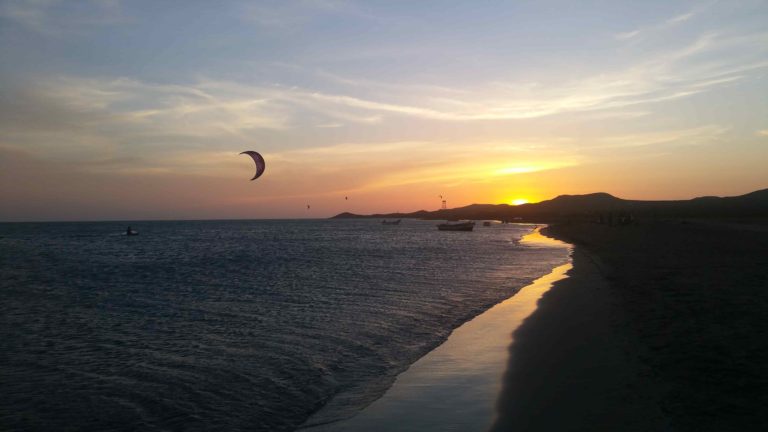Un kitesurf volant devant un coucher de soleil